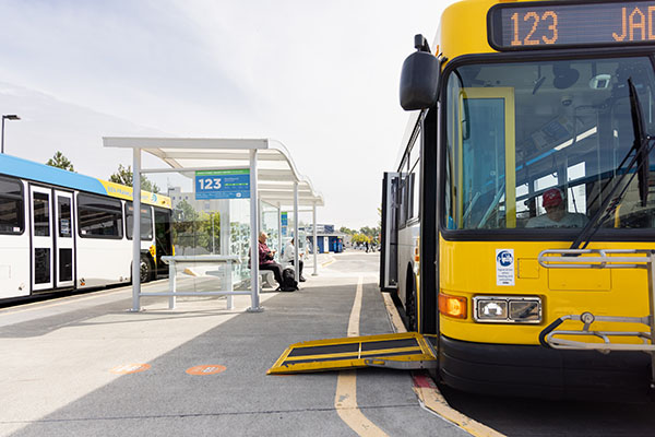 Image of a bus stopped at a bus stop with the accessibility ramp lowered.